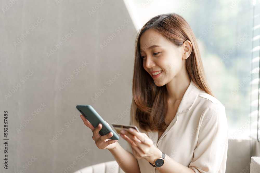 Young pretty asian female using credit card to do online product shopping on her mobile, cashless concept. Young pretty asian female using credit card to do online product shopping on her mobile, cashless concept.