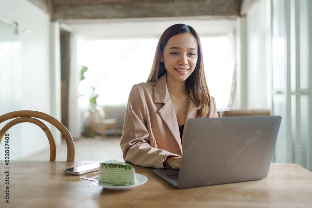 Young happy pretty asian woman using laptop at cafe.