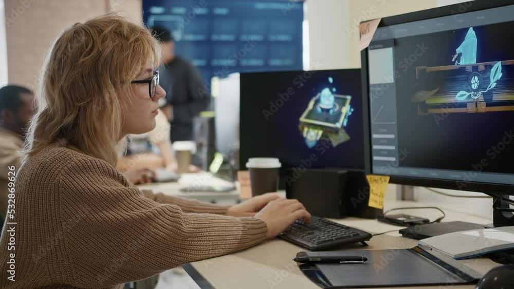 Caucasian female artist designer in glasses draws 3D model for a computer game in the office of a project development studio. Caucasian female artist designer in glasses draws 3D model for a computer game in the office of a project development studio.