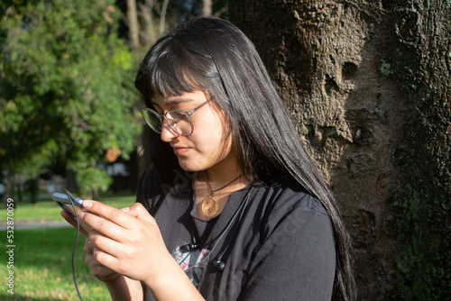 Chica joven mirando su teléfono móvil o celular en la naturaleza photo