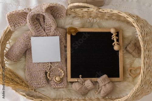 Letter board Baby Announcement with basket. Baby Clothing Mock Up . Space for design . Pregnancy announcement background with blurred . Selective focus photo