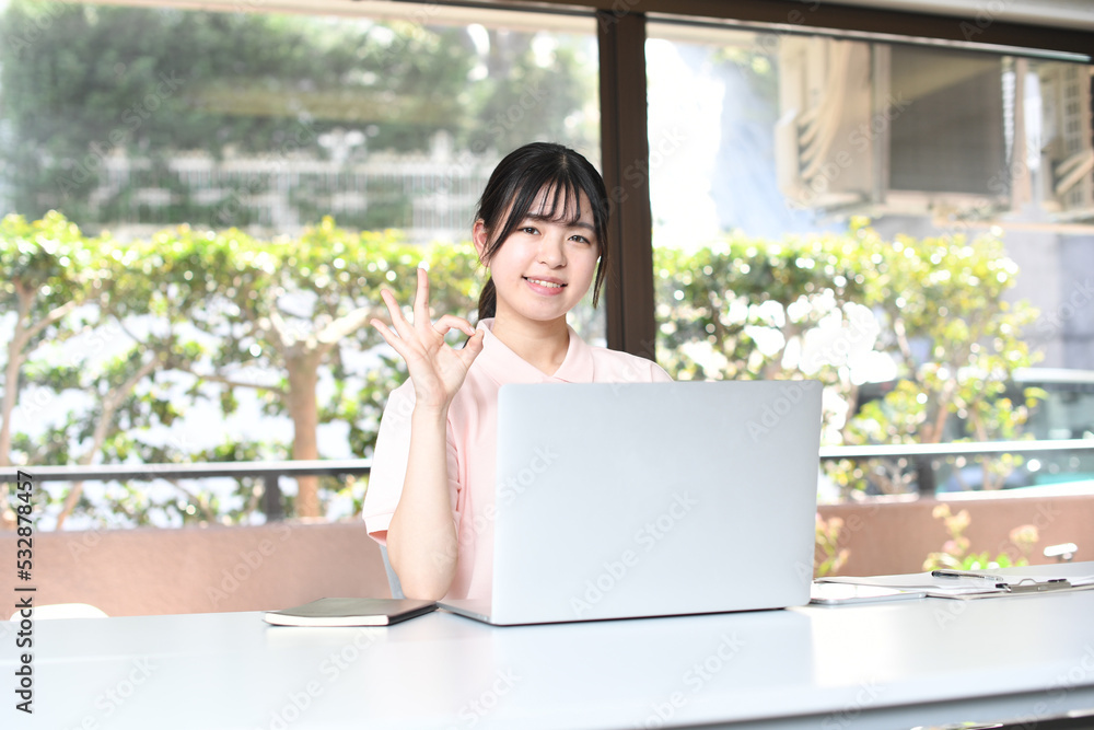 Fototapeta premium パソコンの前でOKをする女性スタッフ