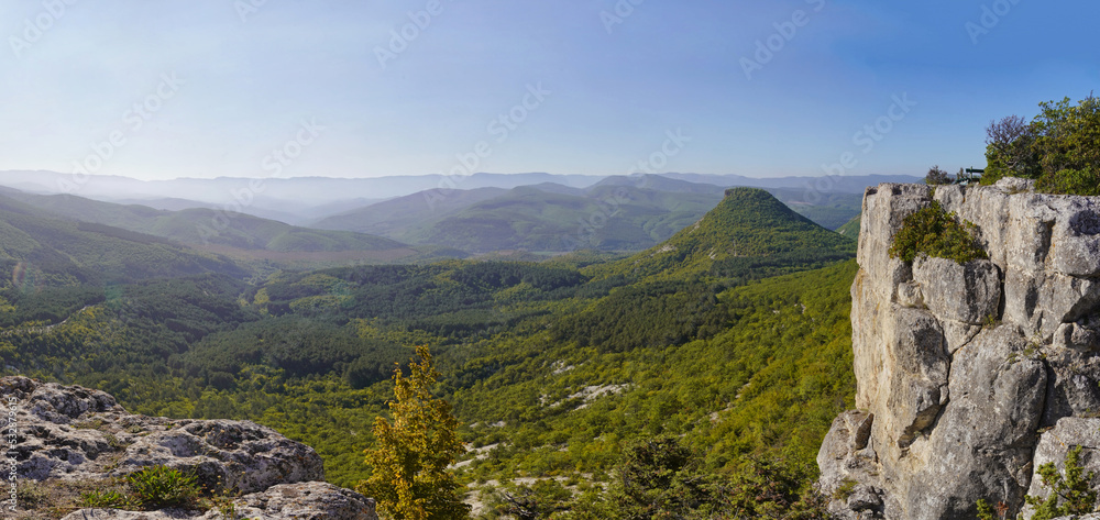 View of the valley and mountains in the early morning mist from the cliff. Tourist observation deck in Bakhchisarai in Crimea. Beautiful landscape. High quality photo.