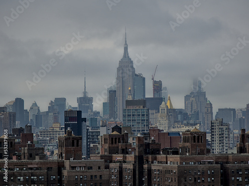 Heavy clouds covering the Empire State Building and Manhattan skyline. Financial district and residential buildings. A shot from Brooklyn Bridge, New York City