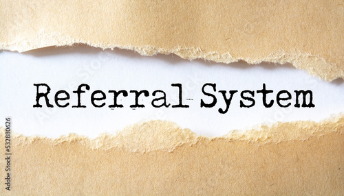 Referral System word written under torn paper, business