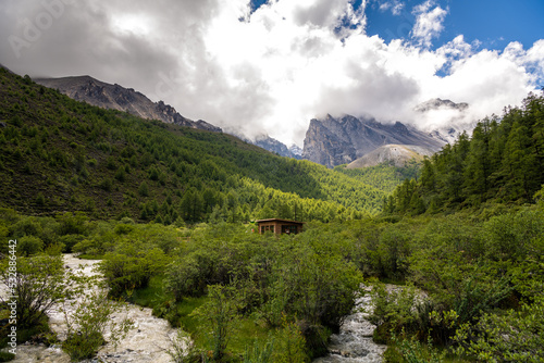 The green meadows  small house and snow mountains in Yading and Daocheng  the last Shangri-La  in Sichuan  China  shot in summer time.