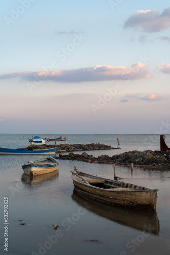 Boats on water, colorful sky and clouds with reflection on water and fishing boats on the sea