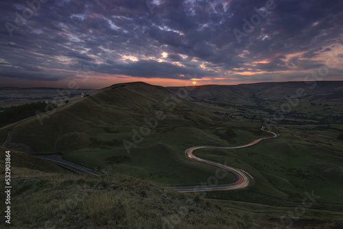 View towards Lords Seat from Mam Tor with car light trails at Sunset. Peak District, Derbyshire photo