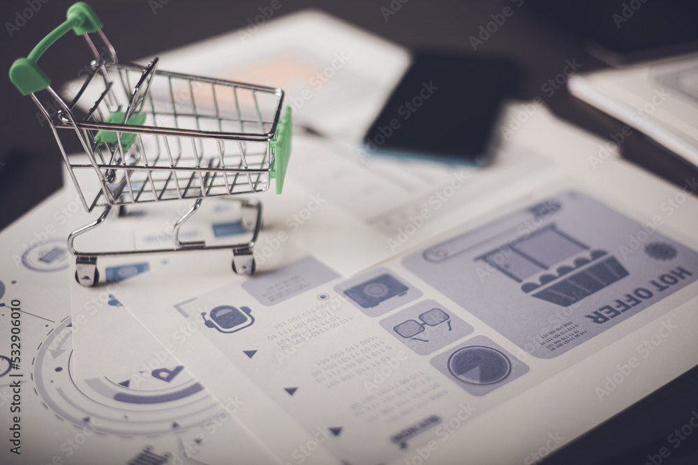 Analysis of online merchandising business reports, with charts and market statistics, shopping carts and promotional items. tabletop, ecommerce concept and online selling website