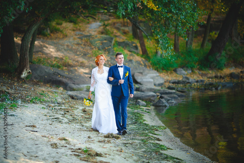 Young beautiful couple in a blue suit and white wedding dress with a bouquet