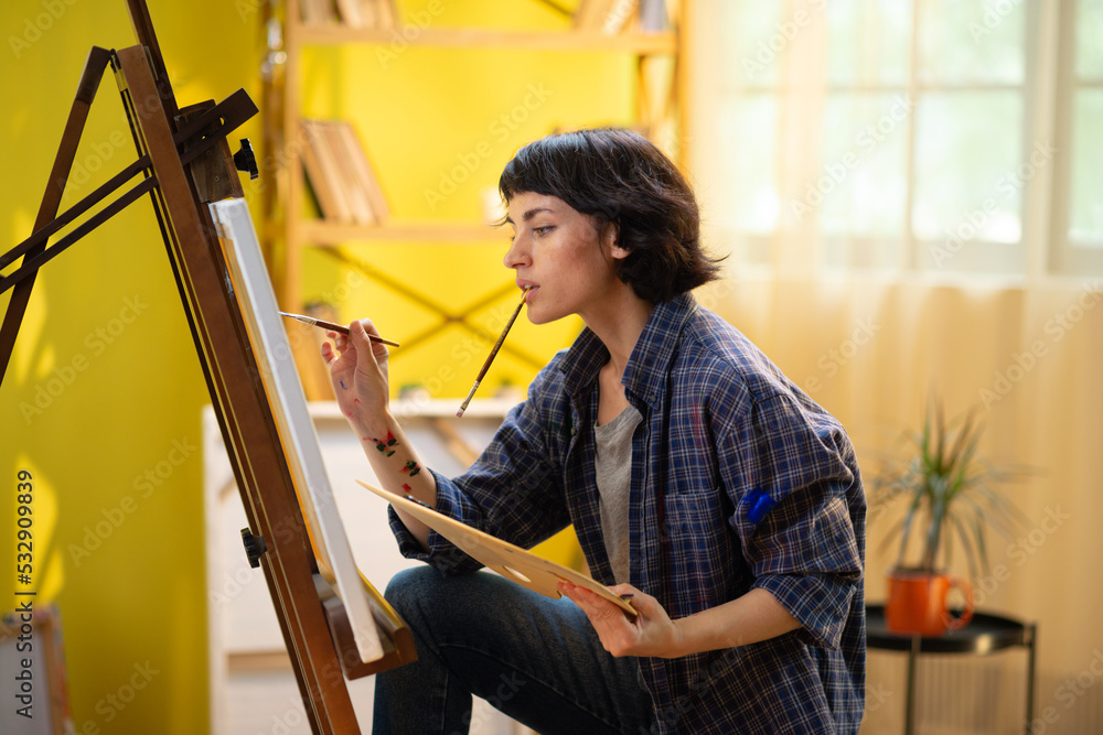 A close up shot of a the back on an artistic woman painting a beautiful piece of art onto a canvas and sitting in a comfortable position A close up shot of a the back on an artistic woman painting a beautiful piece of art onto a canvas and sitting in a comfortable position