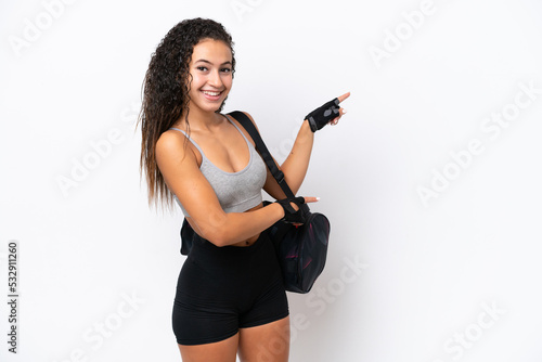 Young sport Arab woman with sport bag isolated on white background pointing finger to the side and presenting a product