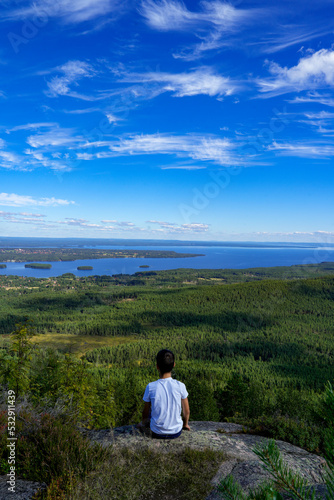 Kind schaut auf dem Berg in die Natur mit Seenlandschaft in Schweden  Skandinavien mit blauem Himmel im Hintergrund und viel Wasser