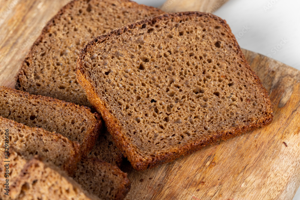 Sliced piece of black rye bread on a board Sliced piece of black rye bread on a board