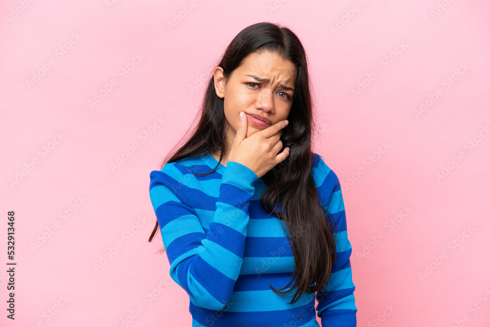 Young Colombian woman isolated on pink background having doubts Young Colombian woman isolated on pink background having doubts