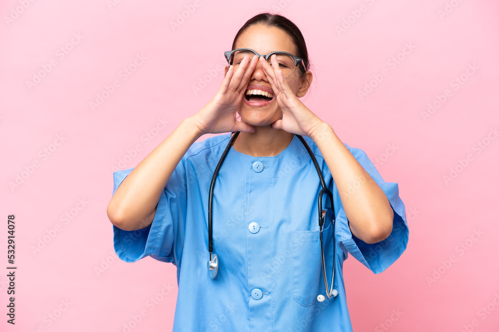 Young nurse Colombian woman isolated on pink background shouting and announcing something Young nurse Colombian woman isolated on pink background shouting and announcing something