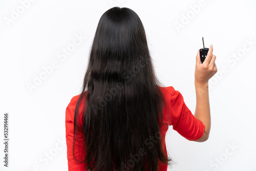 Young Colombian woman holding car keys isolated on white background in back position