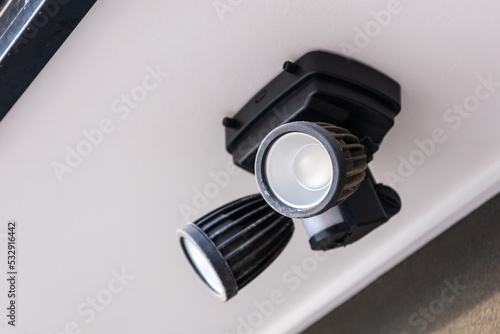 An outdoor security dual head flood light under the roof.
