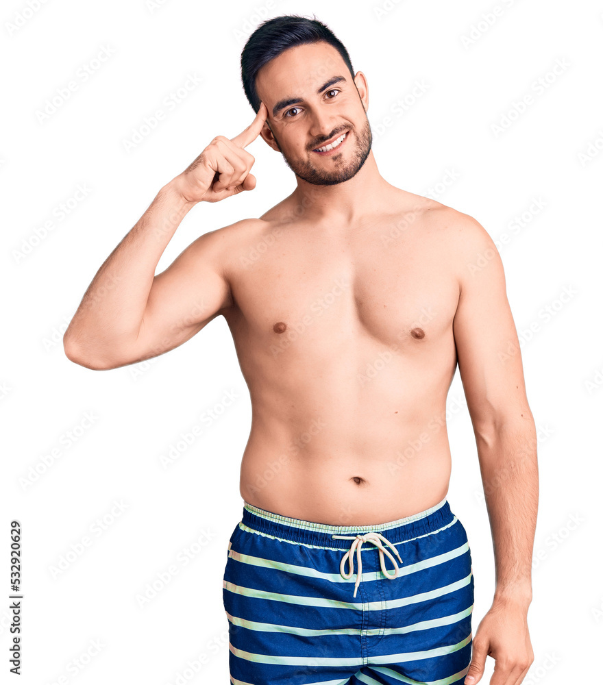 Young handsome man wearing swimwear smiling pointing to head with one finger, great idea or thought, good memory Young handsome man wearing swimwear smiling pointing to head with one finger, great idea or thought, good memory