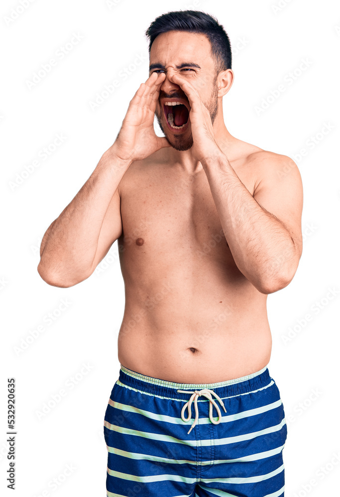 Fototapeta premium Young handsome man wearing swimwear shouting angry out loud with hands over mouth