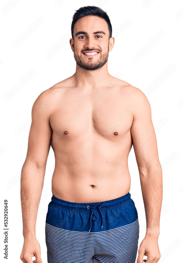 Young handsome man wearing swimwear looking positive and happy standing and smiling with a confident smile showing teeth Young handsome man wearing swimwear looking positive and happy standing and smiling with a confident smile showing teeth