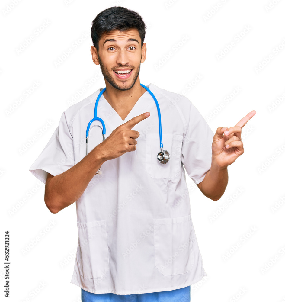 Young handsome man wearing doctor uniform and stethoscope smiling and looking at the camera pointing with two hands and fingers to the side. Young handsome man wearing doctor uniform and stethoscope smiling and looking at the camera pointing with two hands and fingers to the side.