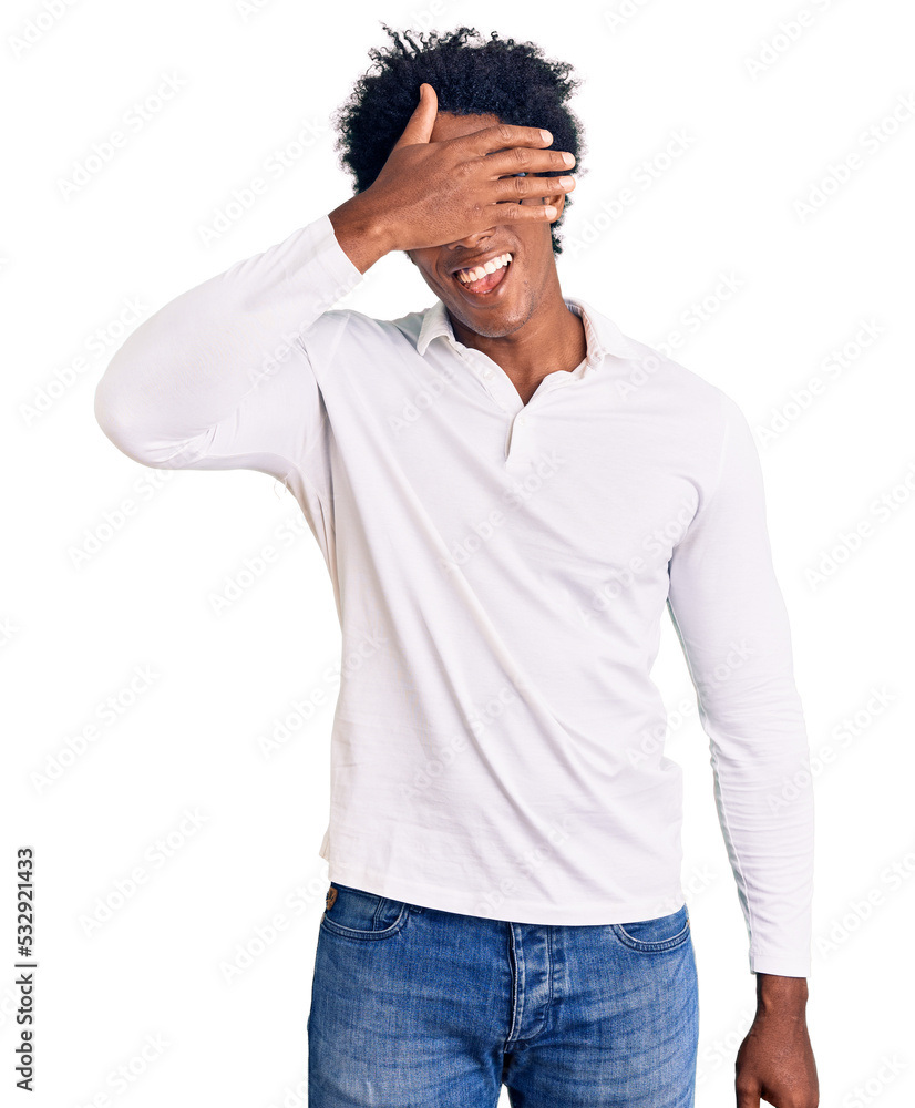 Handsome african american man with afro hair wearing casual clothes and glasses smiling and laughing with hand on face covering eyes for surprise. blind concept. Handsome african american man with afro hair wearing casual clothes and glasses smiling and laughing with hand on face covering eyes for surprise. blind concept.