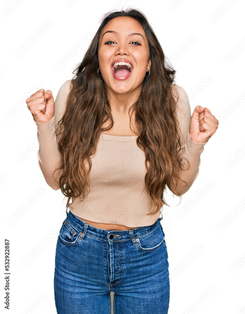 Young hispanic girl wearing casual clothes celebrating surprised and amazed for success with arms raised and open eyes. winner concept. Young hispanic girl wearing casual clothes celebrating surprised and amazed for success with arms raised and open eyes. winner concept.