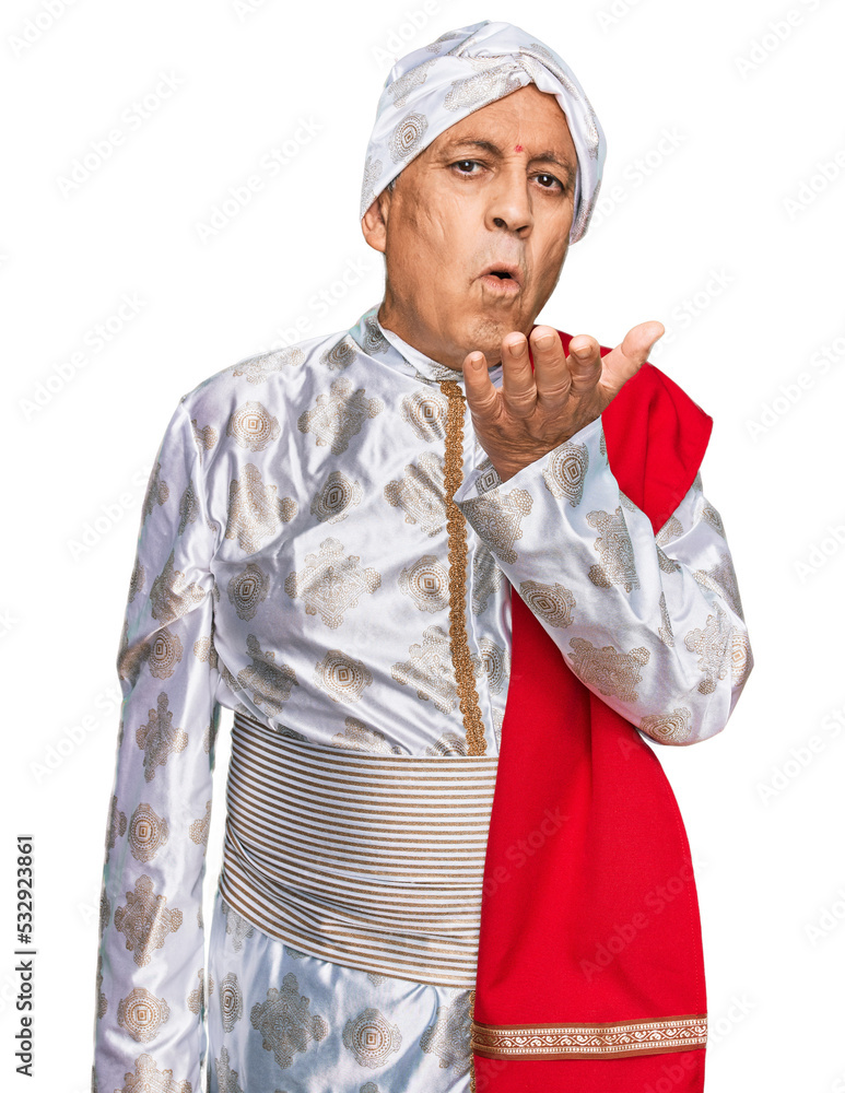 Senior hispanic man wearing tradition sherwani saree clothes looking at the camera blowing a kiss with hand on air being lovely and sexy. love expression. Senior hispanic man wearing tradition sherwani saree clothes looking at the camera blowing a kiss with hand on air being lovely and sexy. love expression.