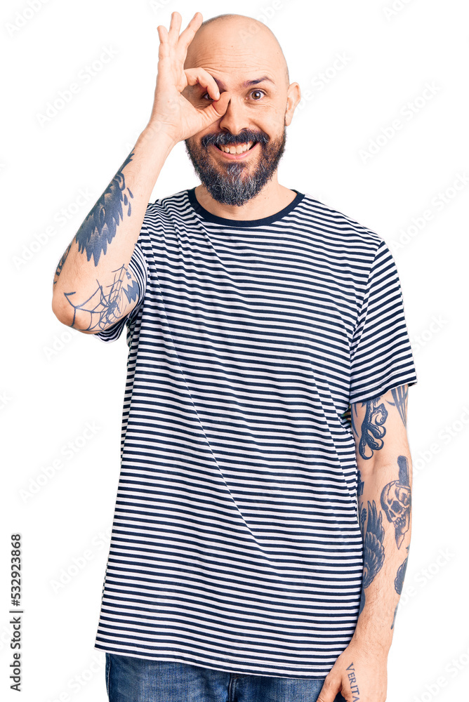 Young handsome man wearing casual clothes doing ok gesture with hand smiling, eye looking through fingers with happy face. Young handsome man wearing casual clothes doing ok gesture with hand smiling, eye looking through fingers with happy face.