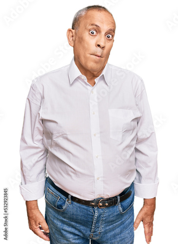 Quadro su tela Handsome senior man wearing elegant white shirt making fish face with lips, crazy and comical gesture