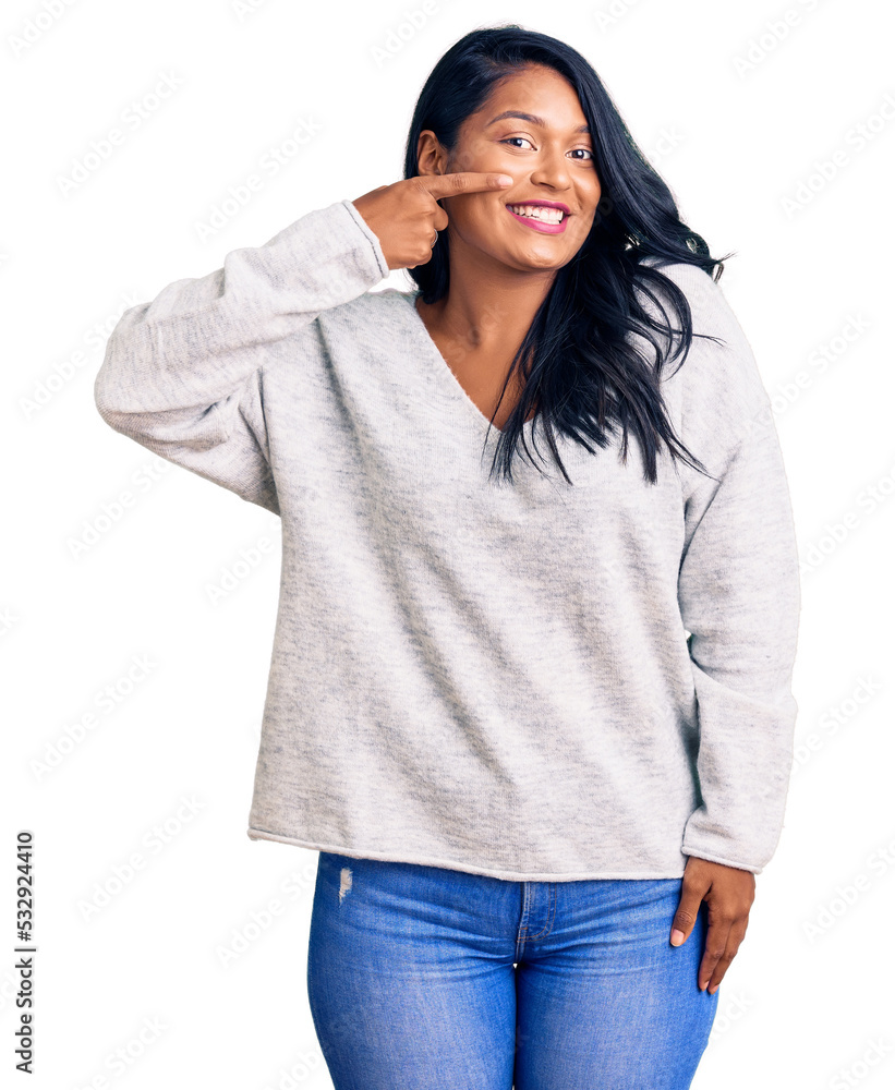 Hispanic woman with long hair wearing casual clothes pointing with hand finger to face and nose, smiling cheerful. beauty concept Hispanic woman with long hair wearing casual clothes pointing with hand finger to face and nose, smiling cheerful. beauty concept