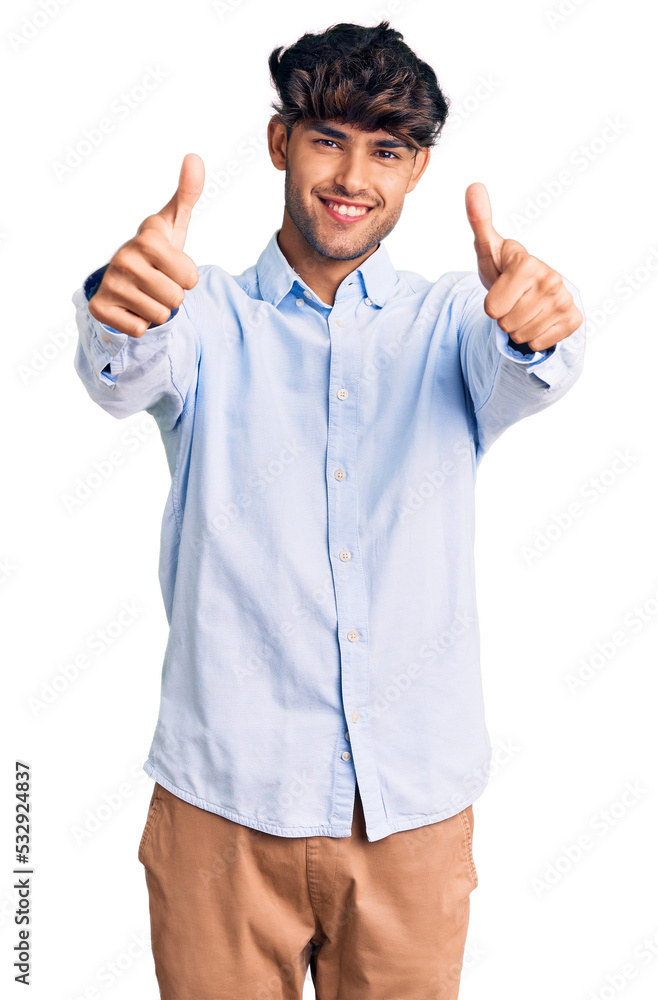 Young hispanic man wearing casual shirt approving doing positive gesture with hand, thumbs up smiling and happy for success. winner gesture. Young hispanic man wearing casual shirt approving doing positive gesture with hand, thumbs up smiling and happy for success. winner gesture.
