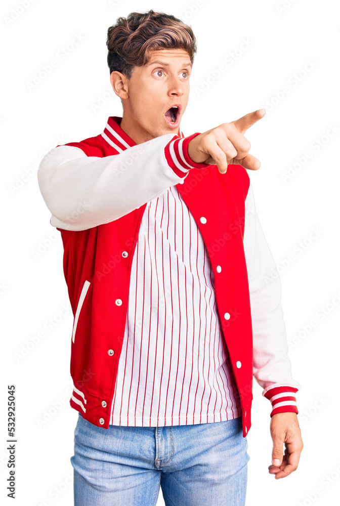 Young handsome man wearing baseball uniform pointing with finger surprised ahead, open mouth amazed expression, something on the front Young handsome man wearing baseball uniform pointing with finger surprised ahead, open mouth amazed expression, something on the front