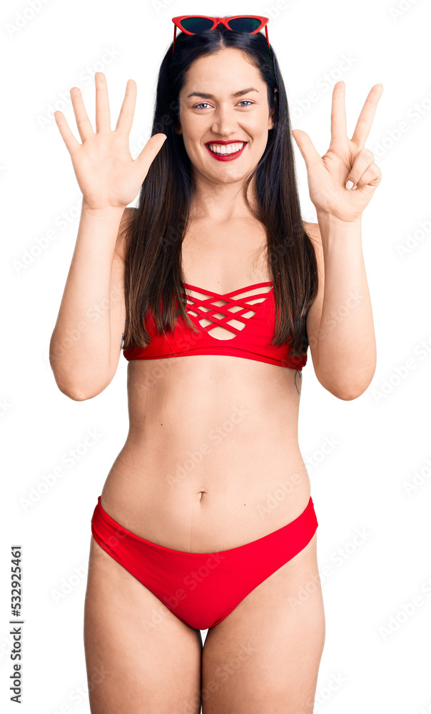 Young beautiful caucasian woman wearing bikini showing and pointing up with fingers number eight while smiling confident and happy. Young beautiful caucasian woman wearing bikini showing and pointing up with fingers number eight while smiling confident and happy.
