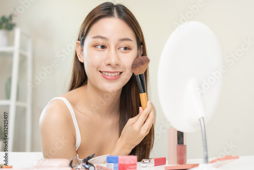 Happy beauty blogger concept  cute asian young woman  girl smile  make up face by applying brush blush powder on her cheek  looking at the mirror. People look with natural fashion style.
