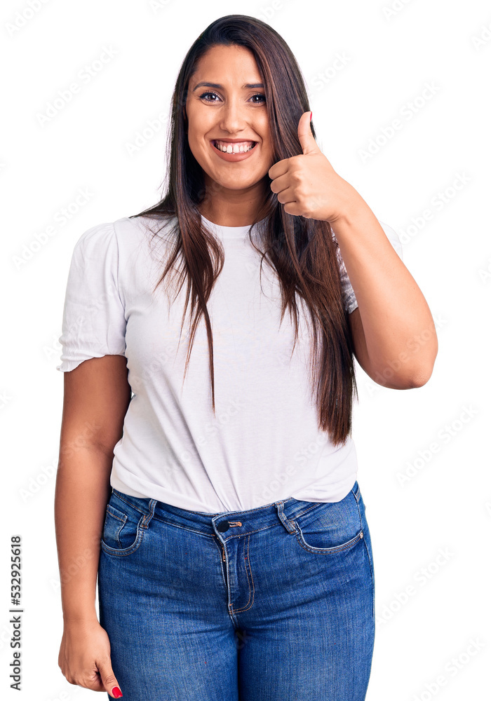 Young beautiful brunette woman wearing casual t-shirt smiling happy and positive, thumb up doing excellent and approval sign Young beautiful brunette woman wearing casual t-shirt smiling happy and positive, thumb up doing excellent and approval sign