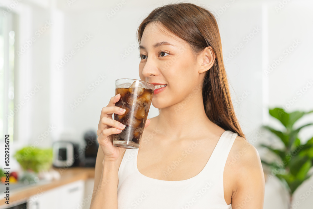 Thirsty, attractive asian young woman, girl drink or sip, holding a glass of cold sparkling water with ice in her hand, in kitchen at home, refreshness people. Temptation of food, health care. Thirsty, attractive asian young woman, girl drink or sip, holding a glass of cold sparkling water with ice in her hand, in kitchen at home, refreshness people. Temptation of food, health care.