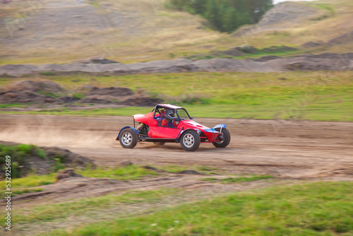A small sports blurred buggy on a rally competition track during weekend training on a warm summer day.