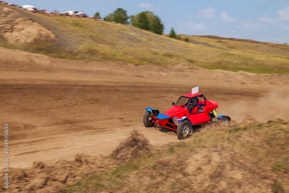 A small sports blurred buggy on a rally competition track during weekend training on a warm summer day. A small sports blurred buggy on a rally competition track during weekend training on a warm summer day.