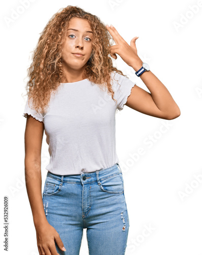 Beautiful caucasian teenager girl wearing casual white tshirt shooting and killing oneself pointing hand and fingers to head like gun, suicide gesture.