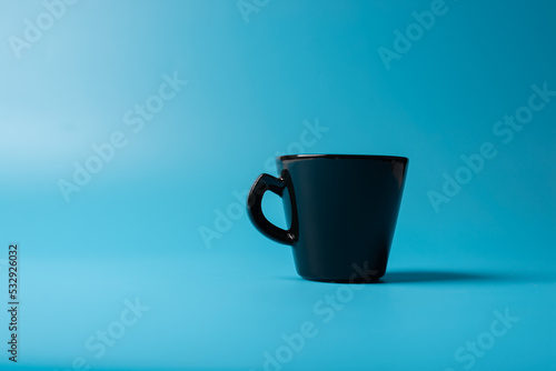 A black cup on a blue background. Minimalism