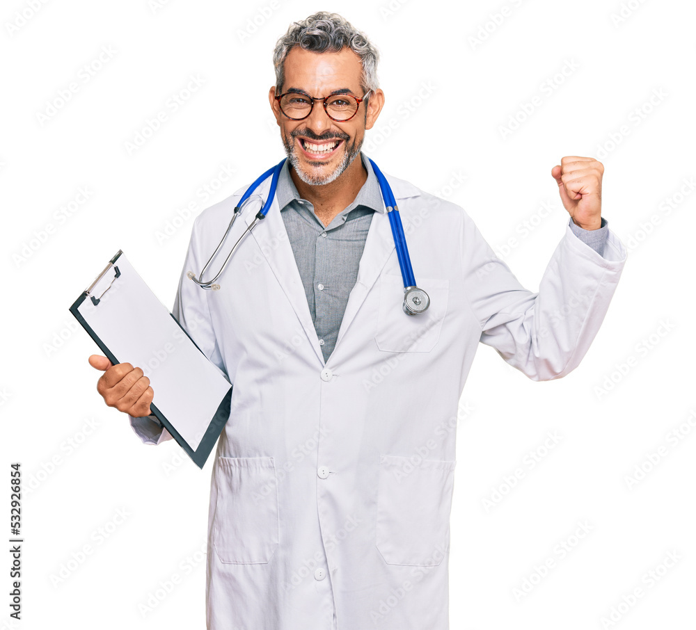 Middle age grey-haired man wearing doctor stethoscope holding clipboard screaming proud, celebrating victory and success very excited with raised arms Middle age grey-haired man wearing doctor stethoscope holding clipboard screaming proud, celebrating victory and success very excited with raised arms