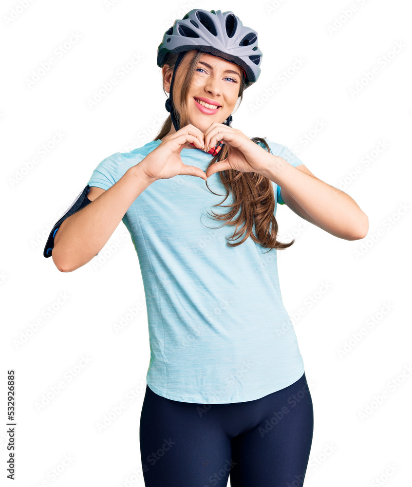 Beautiful caucasian young woman wearing bike helmet smiling in love showing heart symbol and shape with hands. romantic concept. Beautiful caucasian young woman wearing bike helmet smiling in love showing heart symbol and shape with hands. romantic concept.