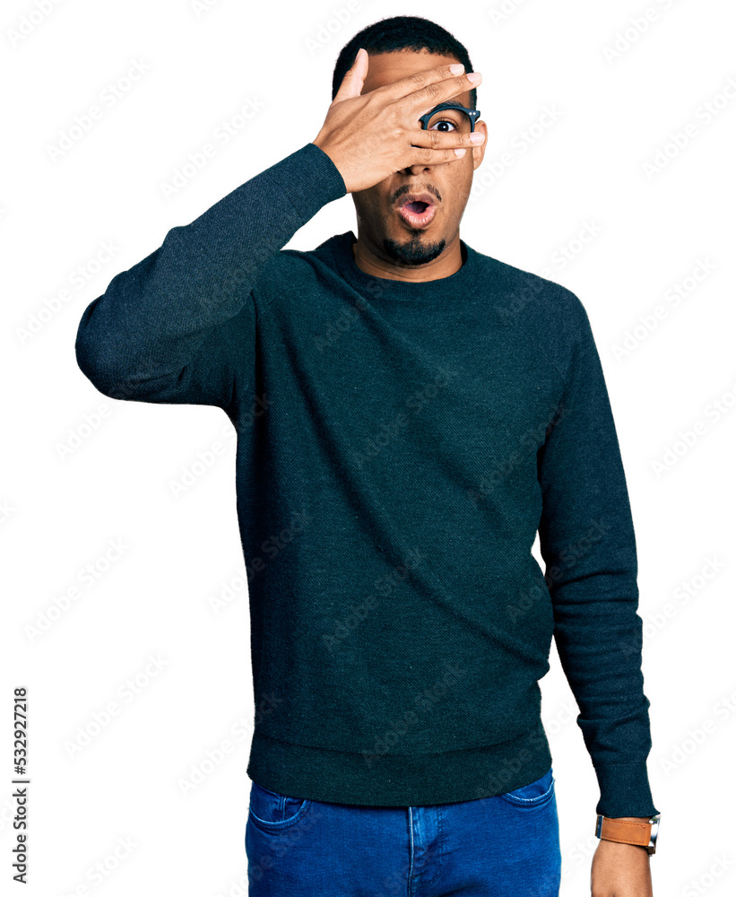 Young african american man wearing casual clothes and glasses peeking in shock covering face and eyes with hand, looking through fingers with embarrassed expression. Young african american man wearing casual clothes and glasses peeking in shock covering face and eyes with hand, looking through fingers with embarrassed expression.