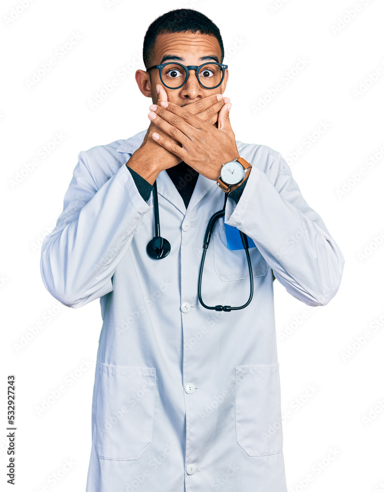Young african american man wearing doctor uniform and stethoscope shocked covering mouth with hands for mistake. secret concept. Young african american man wearing doctor uniform and stethoscope shocked covering mouth with hands for mistake. secret concept.