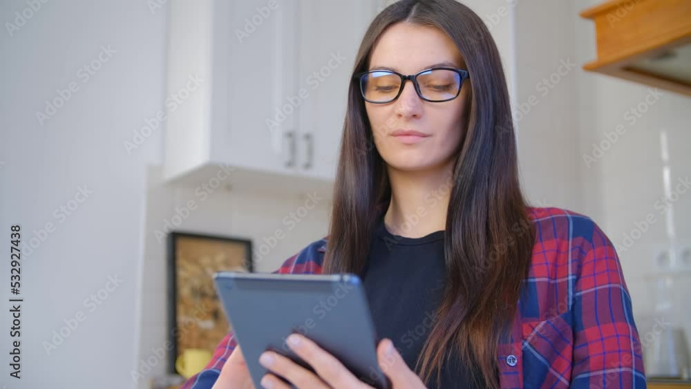 Young woman browsing internet on tablet computer. White female person in nerd glasses reading ebook on modern portable gadget Young woman browsing internet on tablet computer. White female person in nerd glasses reading ebook on modern portable gadget
