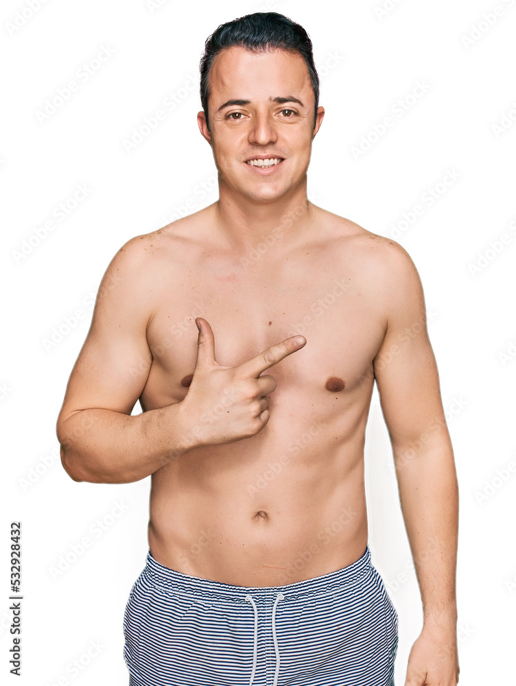 Fototapeta premium Handsome young man wearing swimwear shirtless cheerful with a smile on face pointing with hand and finger up to the side with happy and natural expression