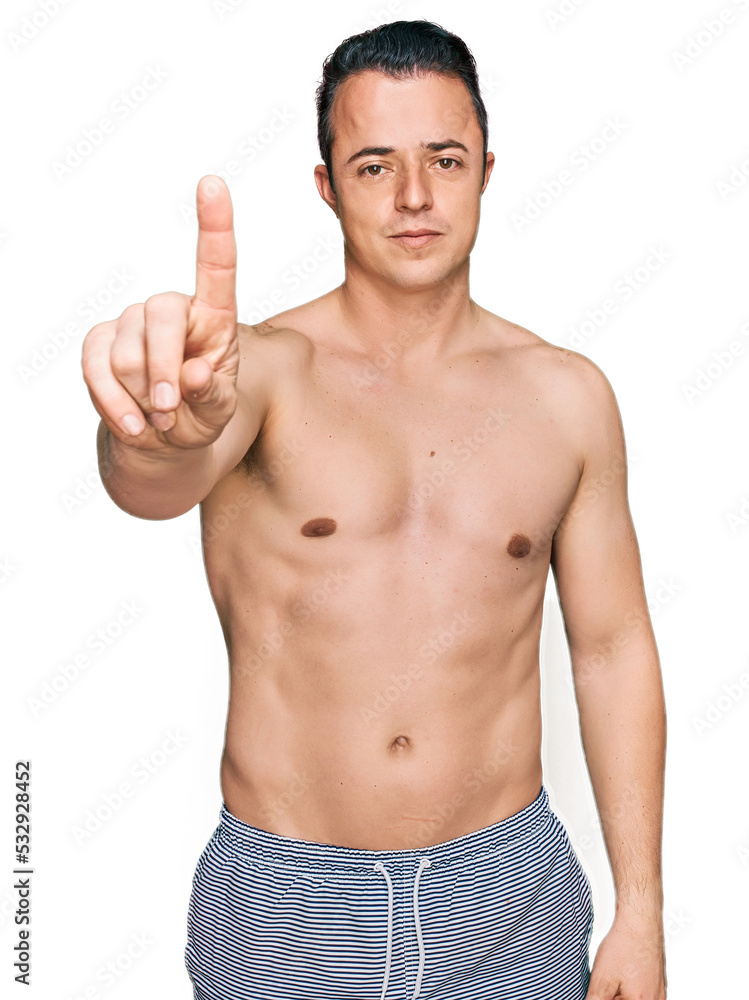 Handsome young man wearing swimwear shirtless pointing with finger up and angry expression, showing no gesture Handsome young man wearing swimwear shirtless pointing with finger up and angry expression, showing no gesture