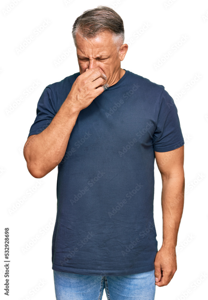 Middle age grey-haired man wearing casual clothes smelling something stinky and disgusting, intolerable smell, holding breath with fingers on nose. bad smell Middle age grey-haired man wearing casual clothes smelling something stinky and disgusting, intolerable smell, holding breath with fingers on nose. bad smell